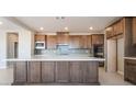 Spacious kitchen featuring an island, wooden cabinets, stainless steel appliances, and tiled backsplash at 769 Cloud Creek St, Henderson, NV 89011