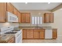 Bright kitchen showcasing granite countertops, white appliances, wood cabinets and shutters at 7916 Lyrebird Dr, North Las Vegas, NV 89084