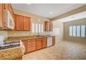 Kitchen featuring wooden cabinets, white appliances, granite counters and tile floors at 7916 Lyrebird Dr, North Las Vegas, NV 89084