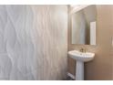 Modern powder room boasts white textured tile, a pedestal sink, and a decorative mirror at 9850 Poplar Point Ave, Las Vegas, NV 89178