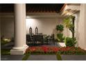 Covered patio with outdoor dining and seating area, accented by lush landscaping and ambient lighting at 1429 Iron Hills Ln, Las Vegas, NV 89134