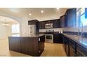 This kitchen has dark cabinets, a stainless steel refrigerator and range, and an island with a granite countertop at 145 Forest Crossing Ct, Las Vegas, NV 89148