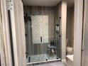 Modern bathroom featuring a glass-enclosed shower with decorative tile and accessible chair at 3447 One Nation Ave, Las Vegas, NV 89121