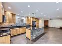 Open-concept kitchen and living area with an island, wood cabinets, black appliances, and brick fireplace at 3557 Wayne Cir, Las Vegas, NV 89121