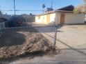 Shows the back exterior of the home with beige walls and a chain link fence at 4430 Judson Ave, Las Vegas, NV 89115