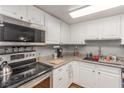 Well-lit kitchen featuring white cabinets, granite countertops, and stainless steel appliances at 5301 River Glen Dr # 205, Las Vegas, NV 89103