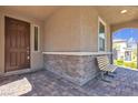 Inviting covered front porch with stone accents, offering a cozy bench and charming exterior details at 6370 Ava Ridge Ave, Las Vegas, NV 89141