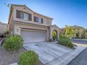 Neutral colored two-story home with two-car garage, desert landscaping, and a covered entryway at 7605 Lake Fork Peak St, Las Vegas, NV 89166