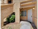 Condo exterior featuring an entry door, landscaped garden, and textured exterior wall at 900 Heavenly Hills Ct # 114, Las Vegas, NV 89145
