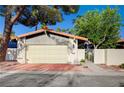 Street view of the home highlighting the two-car garage and gated front entry with lush landscaping at 1905 Plaza Del Padre, Las Vegas, NV 89102