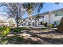 Two-story townhome with white walls, red trim, desert landscaping, mature trees, grass and sidewalk at 225 Pecos Way, Las Vegas, NV 89121