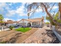 Inviting single-story home featuring an elegant brick driveway, manicured lawn, and a cozy outdoor seating area at 327 Fuente Dr, Henderson, NV 89014