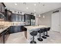 Gorgeous kitchen featuring a large center island, stainless appliances, dark wood cabinetry, and tile floors at 4523 Herbert River Ave, Las Vegas, NV 89141