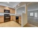 Eat-in kitchen features wood cabinets, black appliances, and breakfast bar with sight lines to the living room at 6160 Rumrill St # 202, Las Vegas, NV 89113