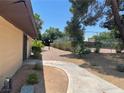 Serene backyard pathway leading to a tennis court with lush green landscaping at 6162 Meadow Vista Ln, Las Vegas, NV 89103