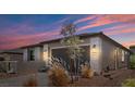 Charming home with a gray exterior, black garage door and desert landscaping at 64 Lake Oasis St, Henderson, NV 89011