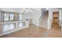 Open-concept living room with tile floors, adjacent to the staircase and featuring an elegant chandelier at 6564 Baroque Ave, Las Vegas, NV 89139