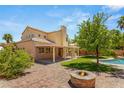 Expansive backyard featuring a covered patio, built-in grill, pool, fire pit and lush landscaping at 215 Sunlight Peak St, Henderson, NV 89012
