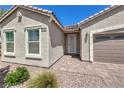 Close up of front door, exterior windows, and two car garage, with gravel and sparse plants at 326 Zenith Crest St, Henderson, NV 89015