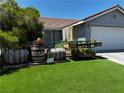 View of the home's front yard, showing artifical lawn and custom wooden barrel landscaping at 3601 Slapton Ave, North Las Vegas, NV 89031