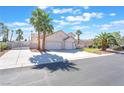 Charming home featuring a three-car garage, arched entryway, manicured lawn, and mature palm trees at 4116 Villa Flora St, Las Vegas, NV 89130