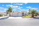 Charming home featuring a three-car garage, arched entryway, manicured lawn, and mature palm trees at 4116 Villa Flora St, Las Vegas, NV 89130