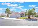 Charming home featuring a three-car garage, arched entryway, manicured lawn, and mature palm trees at 4116 Villa Flora St, Las Vegas, NV 89130