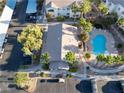 Aerial view of a community pool and spa surrounded by palm trees and lounge chairs near condominiums and covered parking at 5655 E Sahara Ave # 1053, Las Vegas, NV 89142