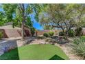 Landscaped backyard with easy keep rocks and green grass area and mature trees at 68 Vista Del Mar St, Henderson, NV 89012