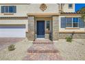 Close up shot of the house entrance that includes a stone facade, blue front door, brick steps, and desert landscaping at 9722 Rocket Grove Ct, Las Vegas, NV 89178