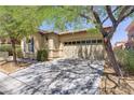 Well-maintained home showcasing mature trees, manicured landscaping, and a two-car garage at 9864 Maspalomas St, Las Vegas, NV 89178