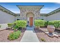Inviting stone archway leading to a solid wood front door, complemented by lush landscaping at 10325 Sweet Fennel Dr, Las Vegas, NV 89135