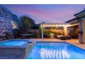 Beautiful backyard with a sparkling pool, jacuzzi, built-in grill, shaded seating area, and desert landscaping at 21 Grand Masters Dr, Las Vegas, NV 89141