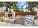 Outdoor kitchen featuring a built-in fireplace, grill, and sink, perfect for entertaining at 5452 Desert Spring Rd, Las Vegas, NV 89149