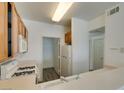 Compact kitchen features wooden cabinets, white appliances and adjacent laundry area at 7163 S Durango Dr # 302, Las Vegas, NV 89113