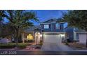 Charming two-story home with blue siding, red shutters, landscaped yard, and a two car garage at dusk at 7728 Whispering River St, Las Vegas, NV 89131