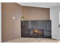 Close up of a modern fireplace with a black marble surround and wood accent wall at 9412 Mount Cherie Ave # 102, Las Vegas, NV 89129
