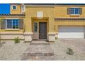 Close up of an inviting yellow home featuring a tile roof and charming brick walkway leading up to the front door at 9712 Rocket Grove Ct, Las Vegas, NV 89178