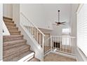 Bright entryway with staircase, white railing, and ceramic tile flooring leads to the living space with a fireplace at 1663 Cloister Ave, Henderson, NV 89014