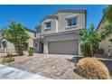 Charming two-story home with a two-car garage, desert landscaping, and a brick driveway at 2024 Mystic Wave Rd, North Las Vegas, NV 89031