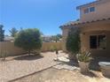 The backyard features desert landscaping, offering a private outdoor space, and a covered patio at 2406 Pebble Springs Ct, Henderson, NV 89074