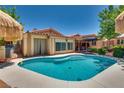 Inviting backyard pool featuring Baja shelf, tropical landscape and thatch umbrellas at 3877 Platis Cir, Las Vegas, NV 89103