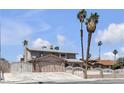 Two-story home featuring a driveway, two palm trees, a front yard, and secure fencing at 6628 Celeste Ave, Las Vegas, NV 89107