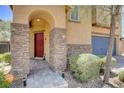 Charming home entrance with stone columns, arched doorway, and a welcoming red front door at 6897 Linda Creek Ct, Las Vegas, NV 89178