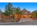 Charming two-story home featuring a three-car garage and beautifully landscaped front yard at twilight at 7033 Twin Forks Peak St, Las Vegas, NV 89166