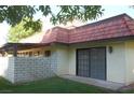 Back exterior with brick details, tiled roof, patio, and green grass at 761 Bourbon St # 5, Pahrump, NV 89048
