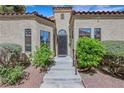 Inviting front entrance with a decorative door, manicured shrubs, and tiled stairs at 7909 Canoe Ln, Las Vegas, NV 89145