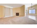 Inviting living room features a cozy fireplace, neutral carpet, and a view leading to the kitchen and dining area at 812 Bitterroot St, Henderson, NV 89002