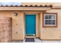 Bright teal front door with a welcome mat on a tan house with brown accents at 11016 Meadow Leaf Ave, Las Vegas, NV 89144