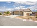 A single-story home with a three car garage and desert landscaping on a sunny day at 171 Weeping Willow Ct, Pahrump, NV 89048